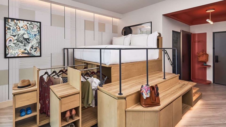 Lofted bed with built-in drawers, open closet, and red entry nook
