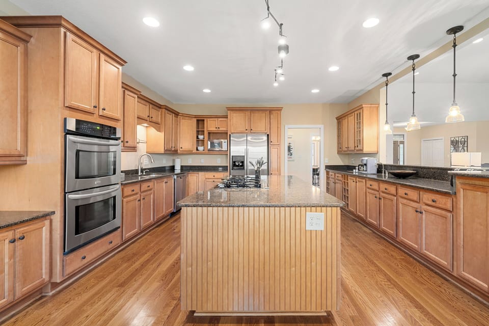 Kitchen has large island with gas cooktop, built-in double ovens, 2 sink areas and plenty of work-space and serving areas.