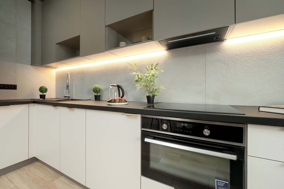 A close-up of a kitchen worktop with under-cabinet lighting, emphasizing sleek modern lines.

