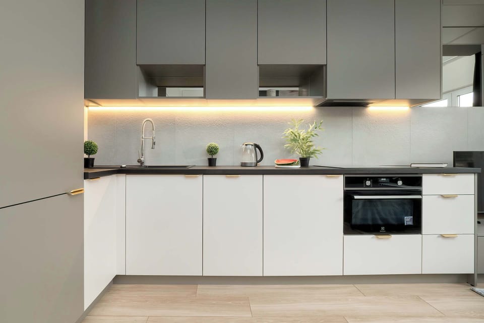 A compact, fully equipped kitchen with white cabinets, integrated appliances, and a dining table partially visible.

