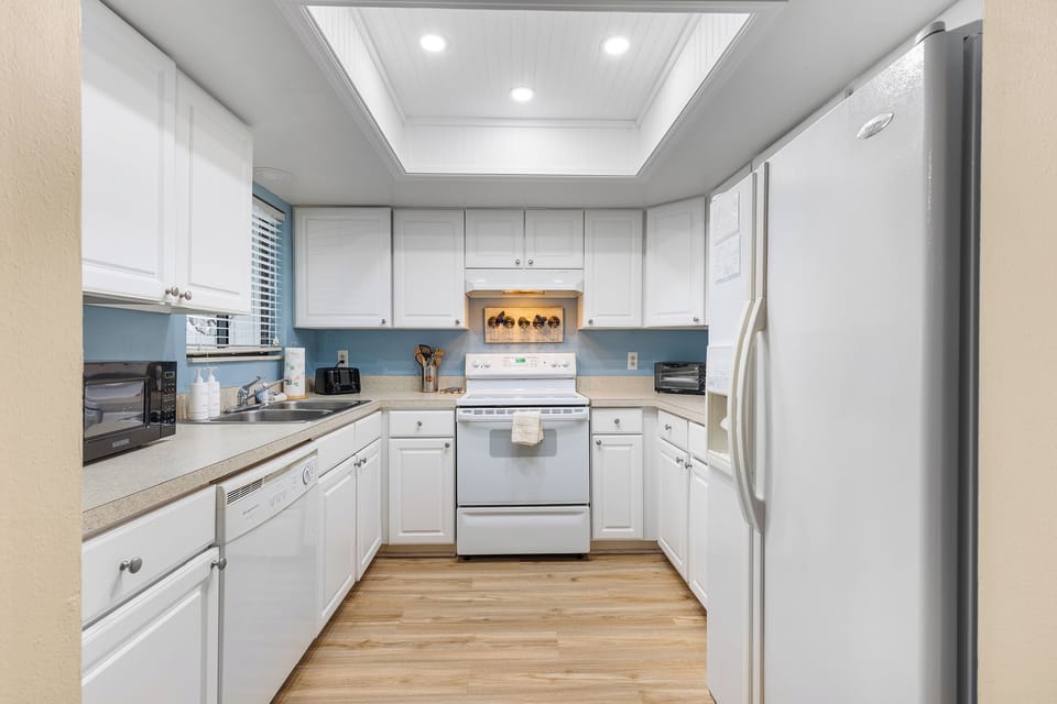 Cook up your favorite seaside meals in this fully equipped, beach-inspired kitchen. Bright white cabinets, modern appliances, and coastal touches make it the perfect spot to gather after a day at the beach. 🌊☀️