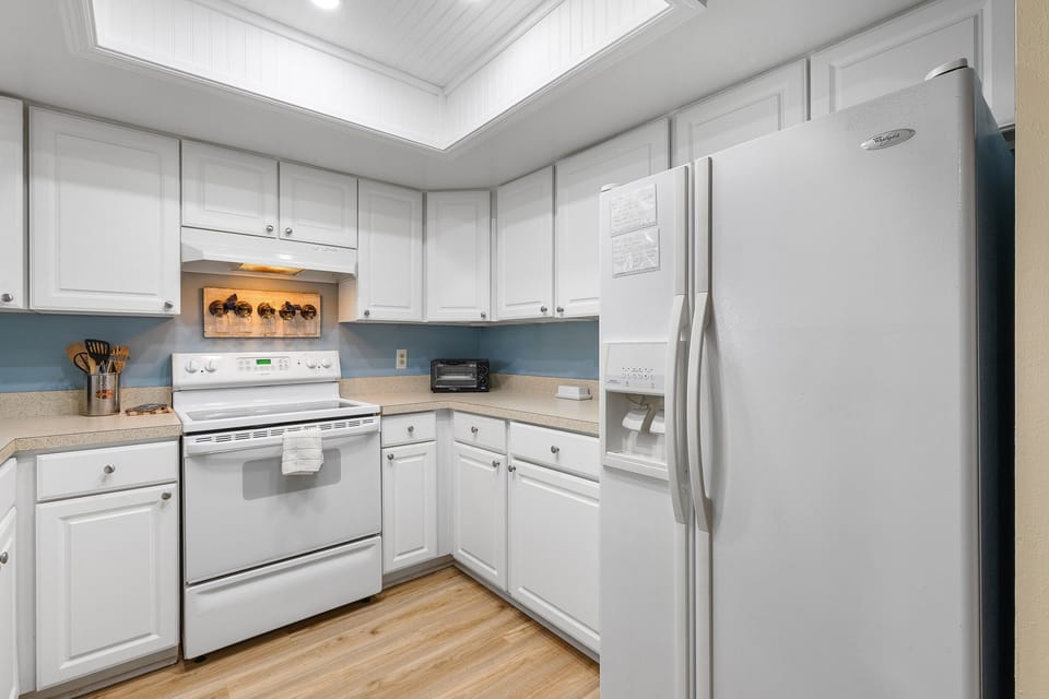 Enjoy a bright, beach-inspired kitchen complete with modern appliances, white cabinetry, and plenty of space to prepare seaside meals after a day at the shore.