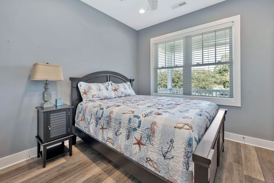 Anchor down in this charming coastal-themed bedroom featuring a comfy queen bed, large window views, and plenty of peaceful vibes.