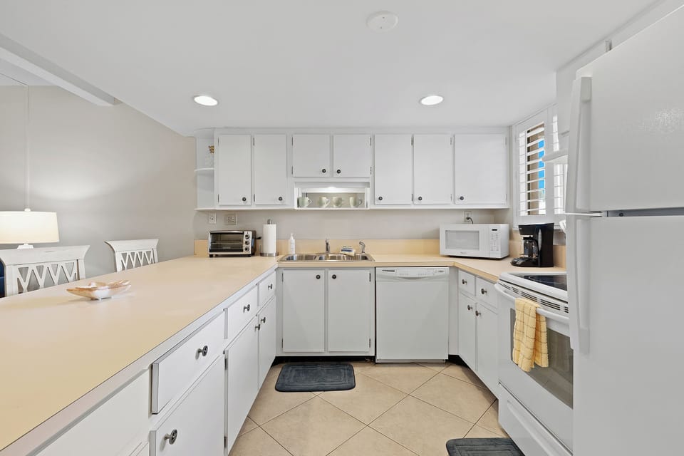 This spacious coastal kitchen features crisp white cabinetry and ample counter space, perfect for preparing beachside meals during your relaxing ocean getaway.