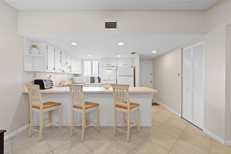 Start your beach day right in this bright, coastal kitchen featuring a spacious breakfast bar—perfect for coffee, quick meals, and casual seaside dining.