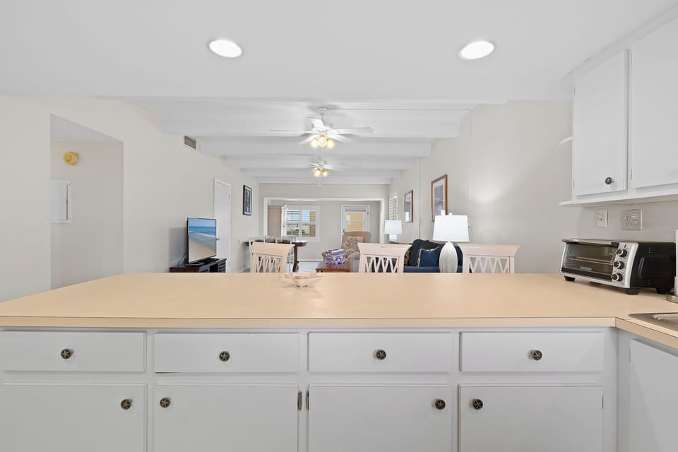Enjoy the open layout of this bright coastal condo, where the kitchen flows seamlessly into the living and dining areas—perfect for relaxing after a sunny beach day.
