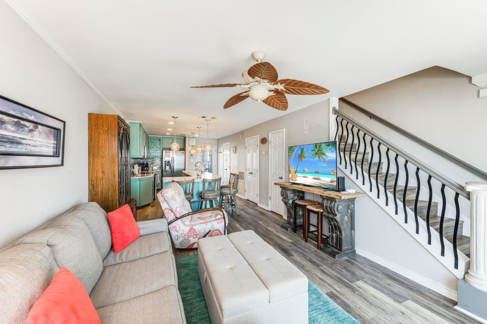 Relax in your beautifully appointed living space with tropical ceiling fan, cozy seating, and turquoise kitchen accents creating the perfect coastal retreat.