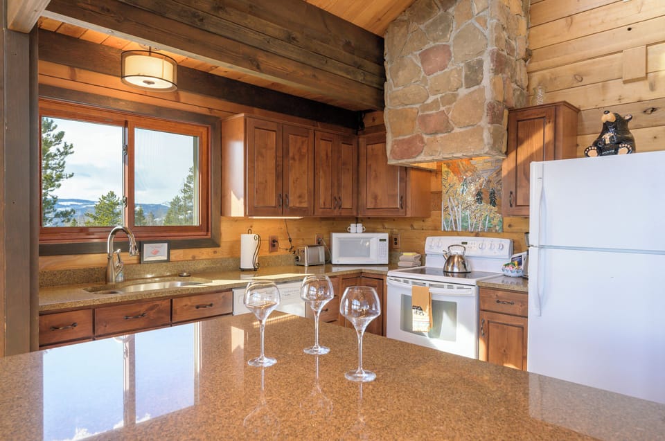 Your rustic mountain kitchen welcomes with warm wood cabinets, granite counters, and stunning valley views through picture windows.