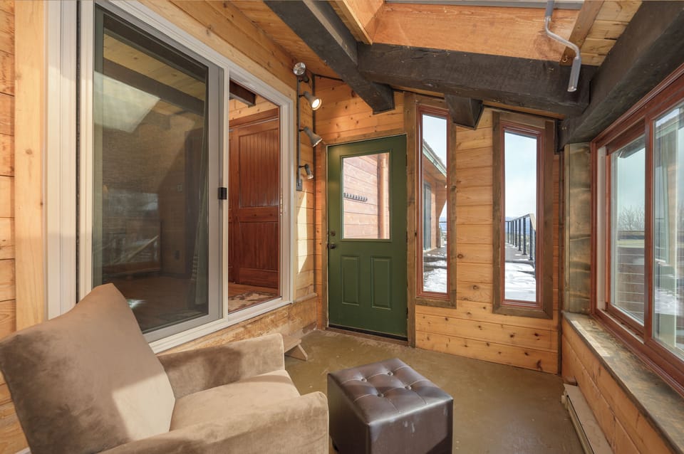 Cozy up in your private sunroom with rustic wood beams and panoramic windows, perfect for morning coffee or evening relaxation.