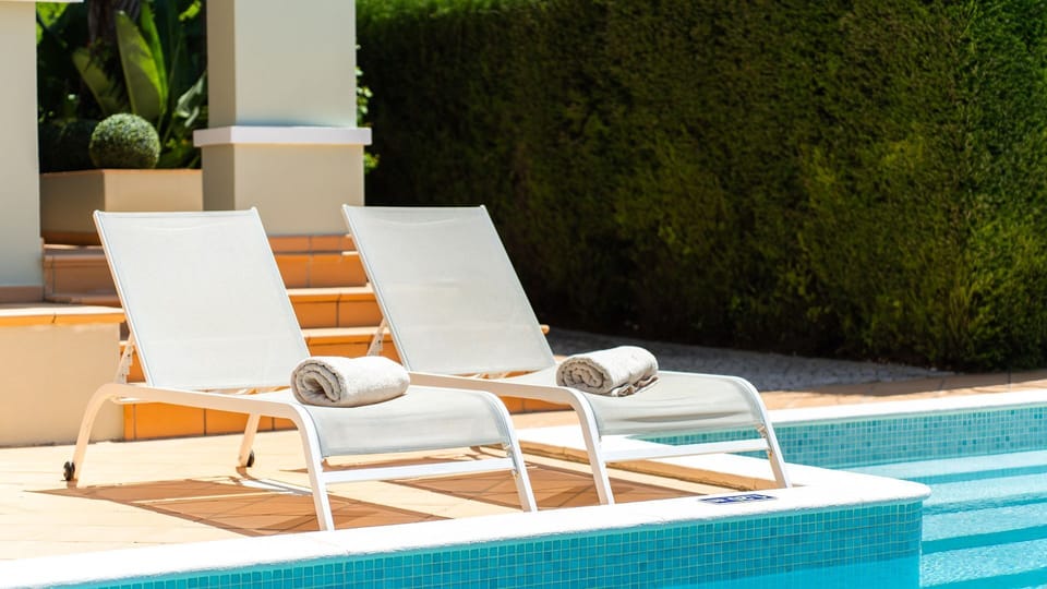 Relaxing outdoor space with comfortable lounge chairs and decorative plants, perfect for leisure moments by the pool.