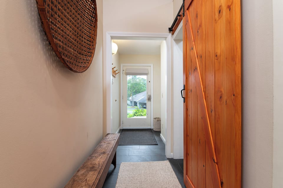 - Bright hallway with barn door and outdoor view   - Functional entryway designed for easy access   - Clean welcoming design with rustic cabin touch