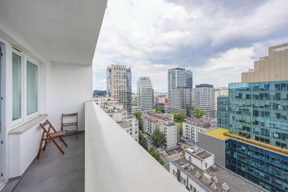 The furnished balcony offers a peaceful space overlooking modern skyscrapers – a perfect spot for morning coffee or evening relaxation.