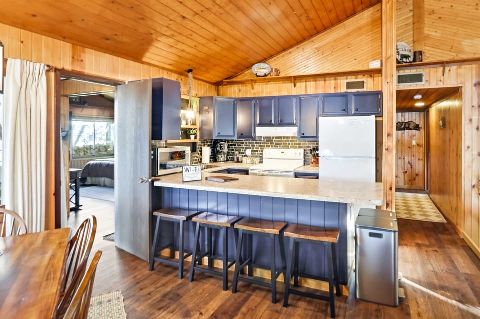 Warm cabin-style kitchen with breakfast bar seating, wood finishes, and easy flow to the dining and living areas.