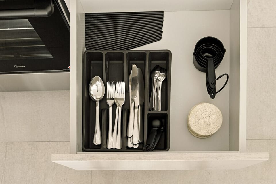 Organized drawer with cutlery, measuring spoons, and kitchen essentials.