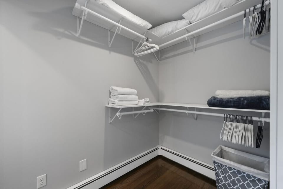Walk-in closet with ample shelving, hangers, and extra linens for guest convenience.