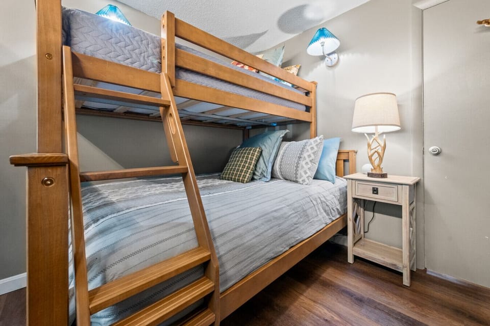 Family-friendly bunk room with full-over-full bunk beds and twin top bunk, crib, reading nook, Roku TV, blackout curtains, and full-size closet. Cozy space designed for kids, families, and relaxing after White Mountains adventures.
