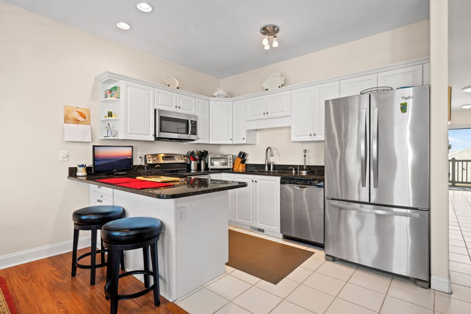 Your fully-equipped kitchen awaits with stainless steel appliances, granite counters, and breakfast bar for morning coffee.