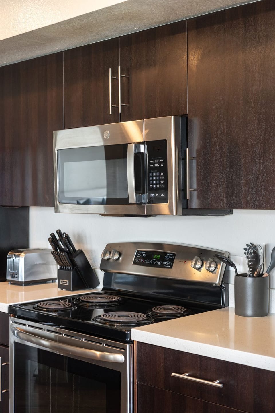 This modern kitchen features dark wood cabinetry and stainless-steel appliances.