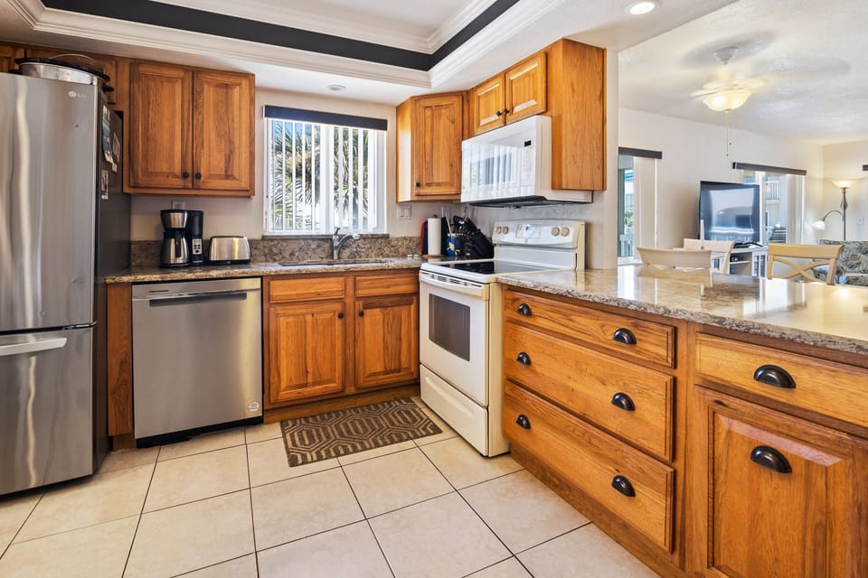 Cook with ease in this spacious, beachside kitchen featuring stainless steel appliances, wood cabinetry, and ample counter space—perfect for preparing fresh meals during your coastal stay.