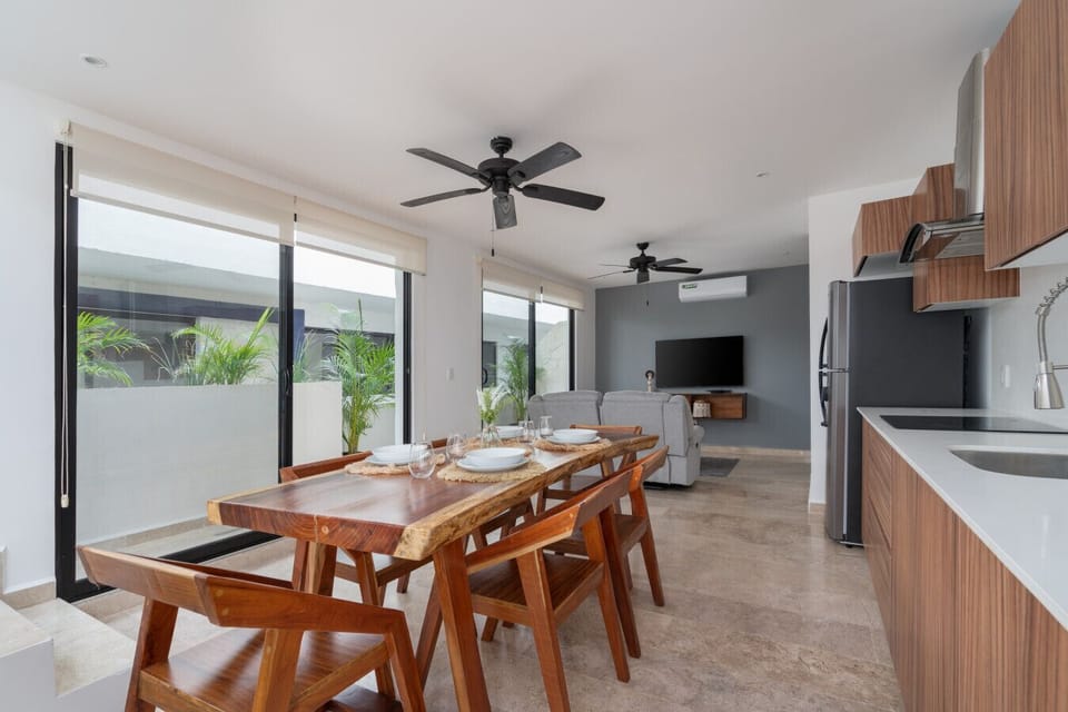 Stylish dining space with greenery, natural light, and seating for 6.