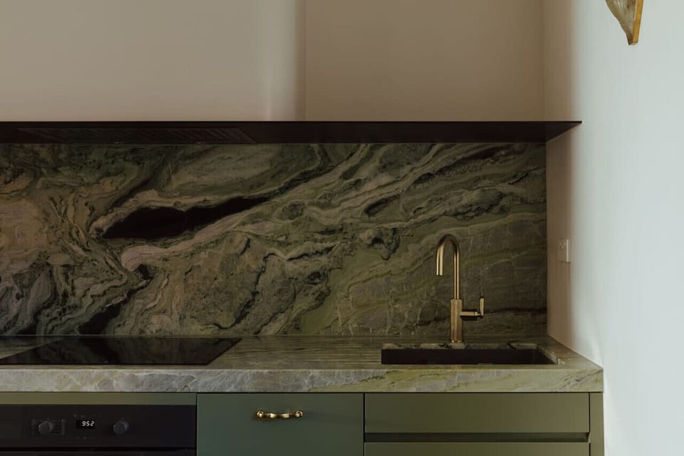 Striking stone benchtops and refined tapware give the kitchen a bold, design-led feel.