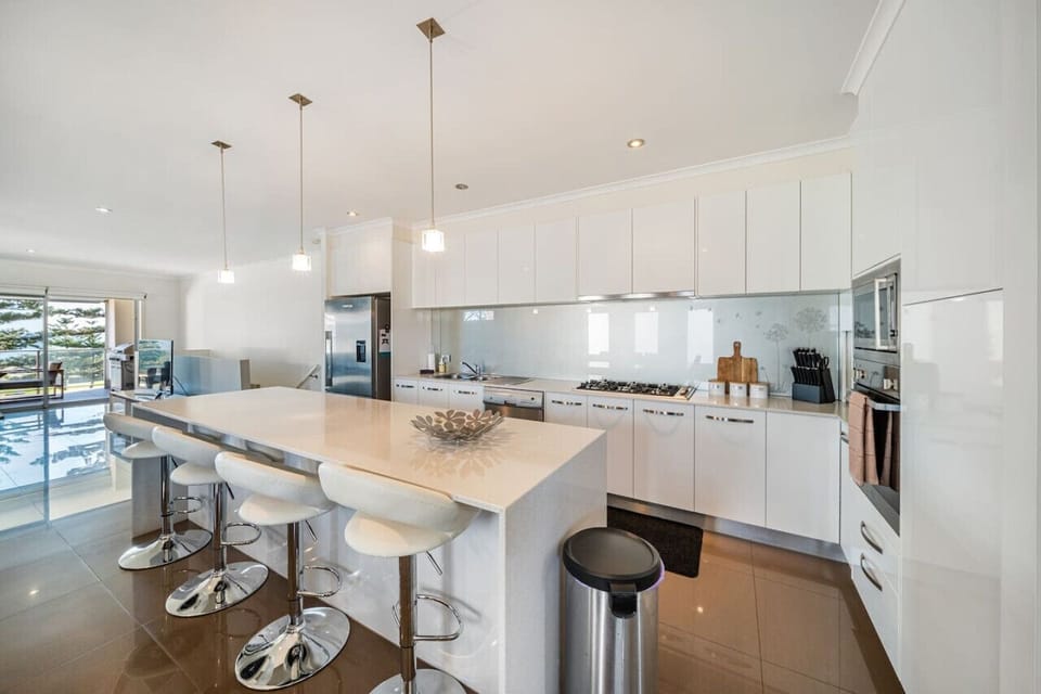 Gather around the generous kitchen island for casual breakfasts, coffee catch-ups, or evening drinks while meals are prepared in the bright contemporary kitchen.