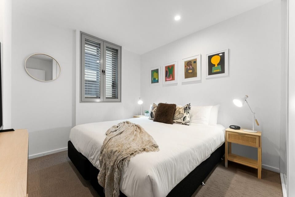 Retreat to the primary bedroom, where a king bed, Smart TV with Netflix and streaming services, and soft, neutral styling create a comfortable space to recharge after a day exploring Adelaide`s East End.