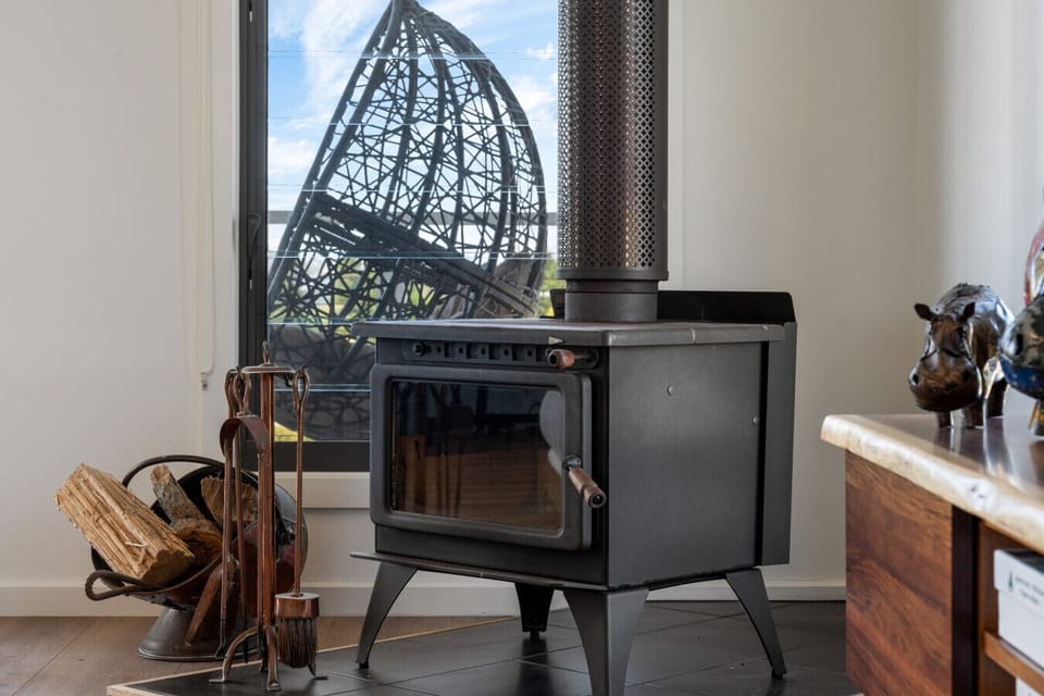 Warm up beside the wood fireplace in the living area, where stacked firewood and comfortable sofas invite slow evenings indoors.