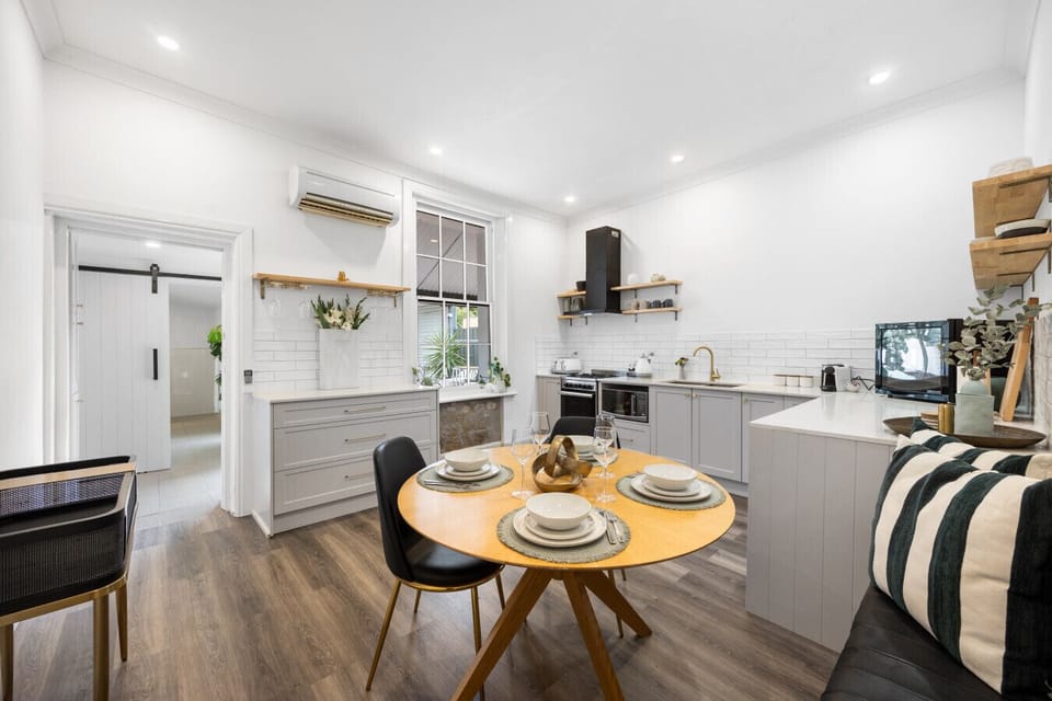 Cook, dine, and connect – the fresh white kitchen opens into a warm dining nook perfect for memorable meals.