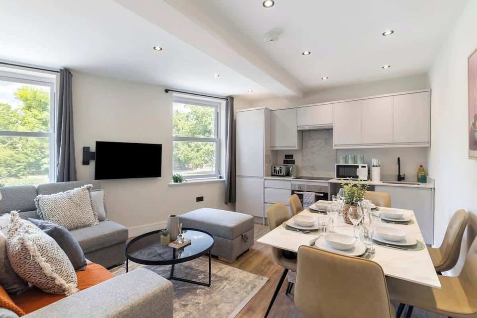 - Open plan living room with sectional sofa, TV, and dining table  
- Bright space connects to fully equipped kitchen for convenience  
- Perfect Airbnb rental for group gatherings and family meals  
