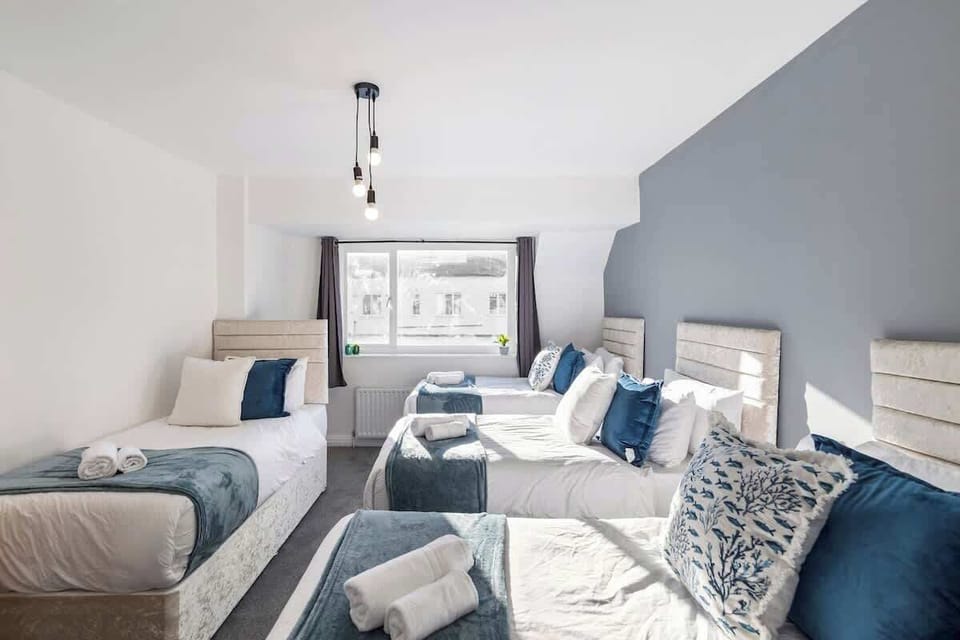 - Large bedroom with four single beds for groups  
- Soft blue accents create a calm cozy atmosphere  
- Bright window light makes mornings feel cheerful  