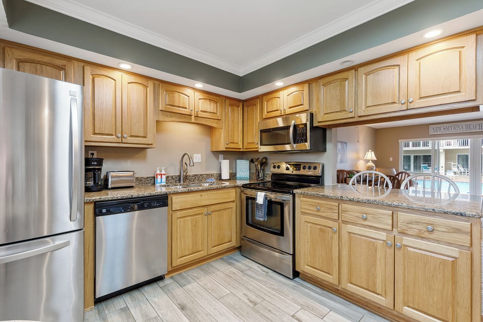 Cook with ease in this modern, beach-style kitchen featuring stainless appliances and ample counter space—perfect for meals and snacks during your New Smyrna Beach stay.