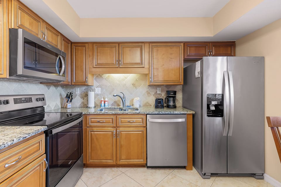 Prepare delicious meals in this modern beachside kitchen featuring stainless steel appliances, granite countertops, and all the essentials for a relaxing coastal stay.