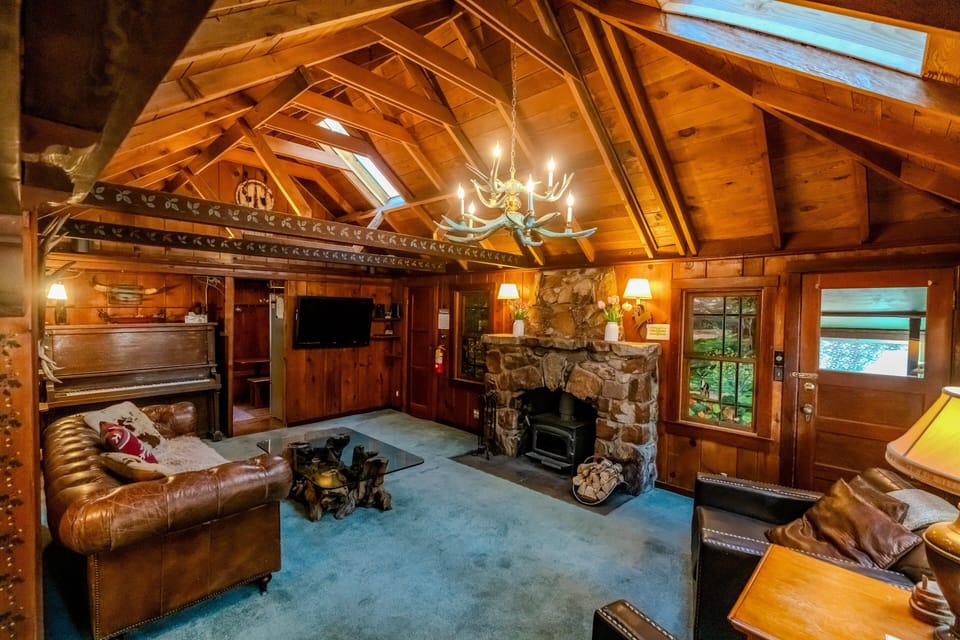 Cozy living room featuring a stone fireplace, comfortable leather seating, and authentic cabin ambiance ideal for relaxing evenings indoors.