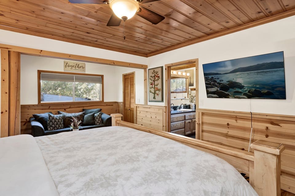 Unwind in the spacious primary bedroom featuring warm wood accents, comfortable bedding, and relaxing mountain decor. A peaceful place to recharge after a day exploring Big Bear Lake or hitting the slopes.
