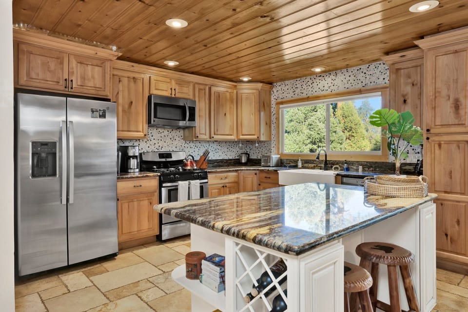 Prepare meals in the fully equipped kitchen featuring stainless appliances, granite countertops, and a central island for extra seating. Ideal for cooking family dinners, morning coffee, or snacks before heading out to adventure.