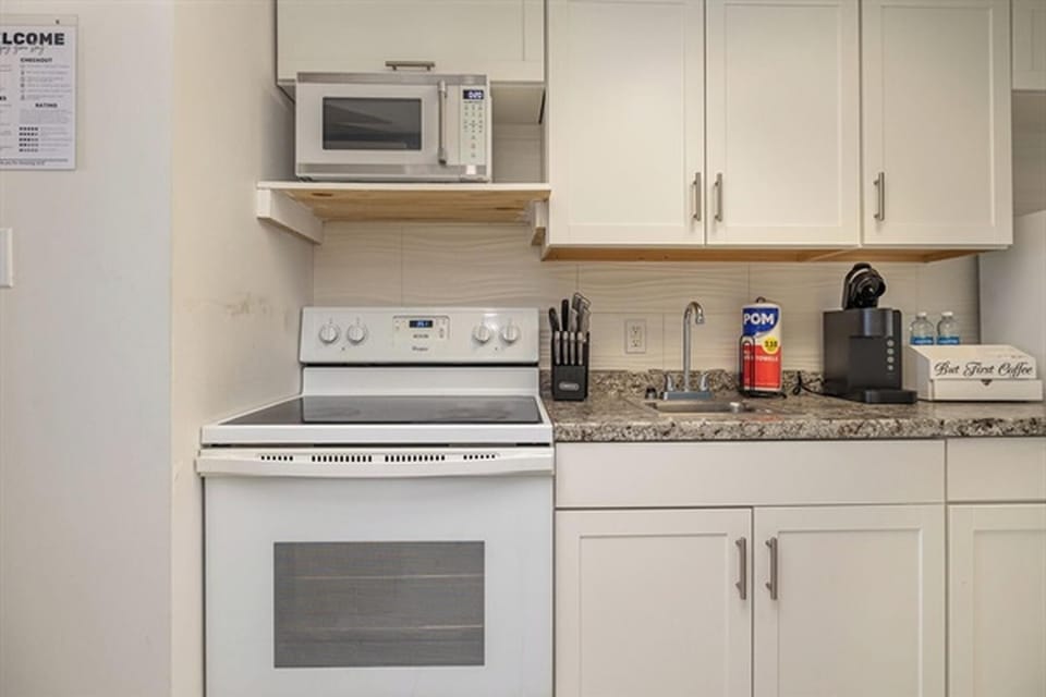 Microwave, stove, and cabinetry with all cooking essentials
