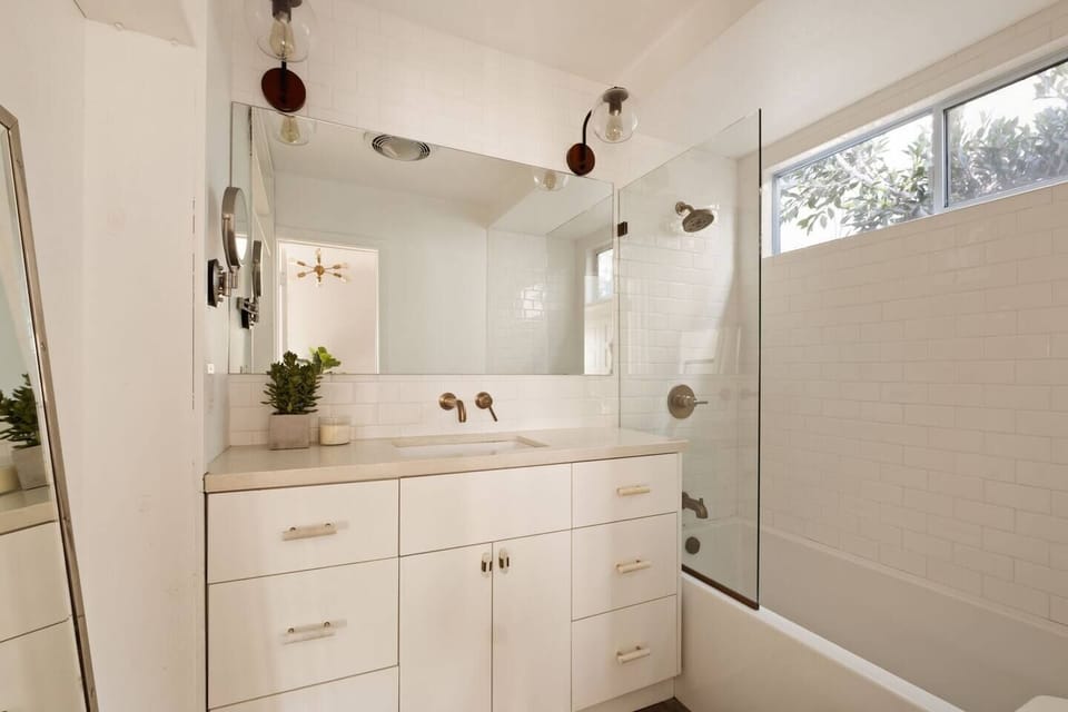 Bright modern bath with sleek vanity, glass shower, and natural light
