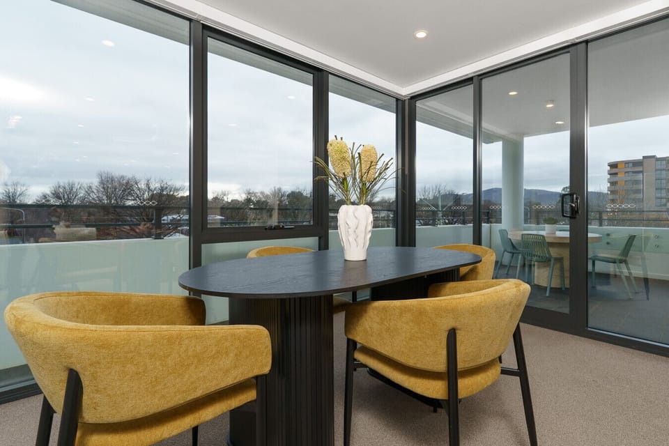 Modern dining space with mustard chairs and scenic balcony views.