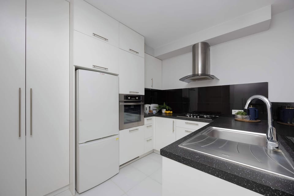 A wide view of the kitchen and dining area showing modern appliances, ample counter space, and light wood flooring for a cozy feel.
