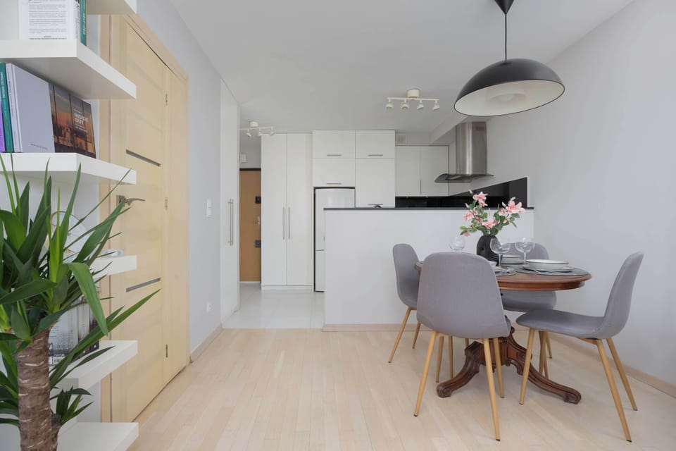 The open kitchenette and dining space with a white modern kitchen, black countertops, and a small dining table with chairs nearby.