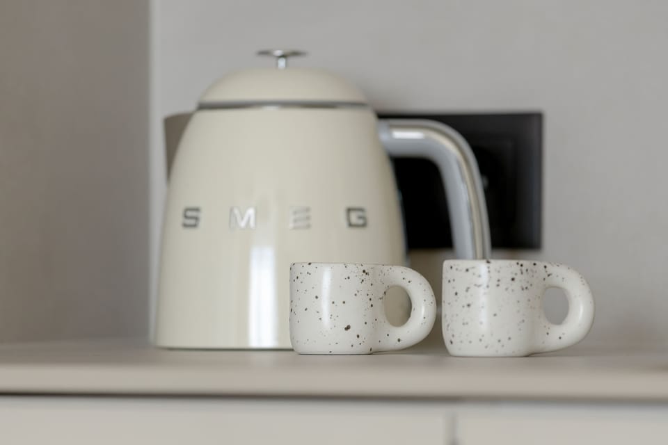 An electric kettle and mugs on the kitchen countertop.