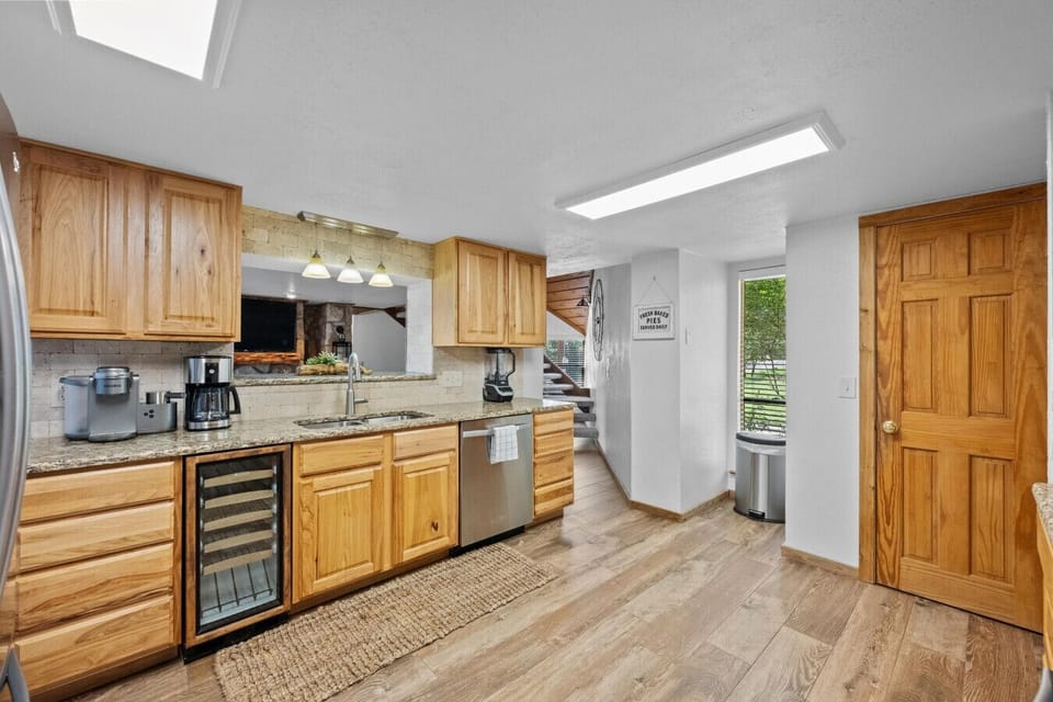 Bright, fully stocked kitchen with generous counters and a window overlooking the cozy living room—stay connected while you cook.