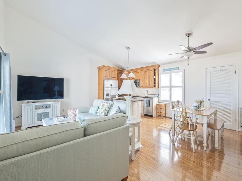 Bright open-plan living area with plush seating, smart TV, and natural wood finishes.
