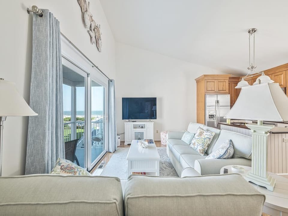 Airy living and dining space with sliding glass doors that lead to a furnished balcony.