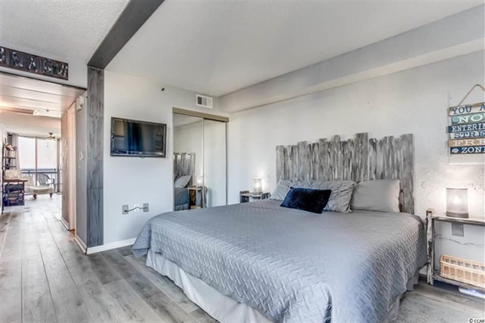 Bedroom with soft lighting, wall-mounted TV, and calming neutral tones