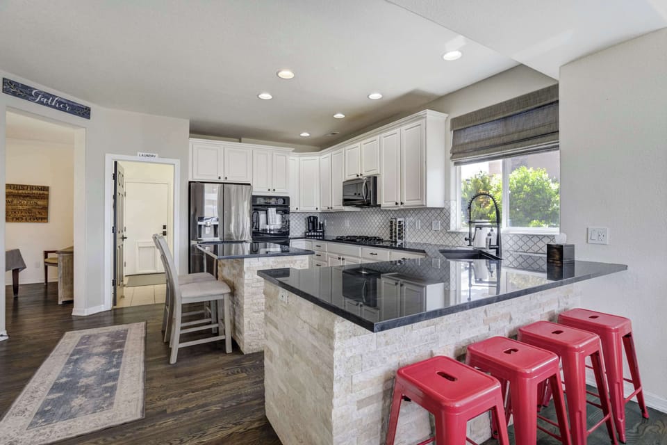 Bright, spacious, and fully equipped—featuring white cabinetry, granite countertops, stainless steel appliances, and a large island with seating for five.


