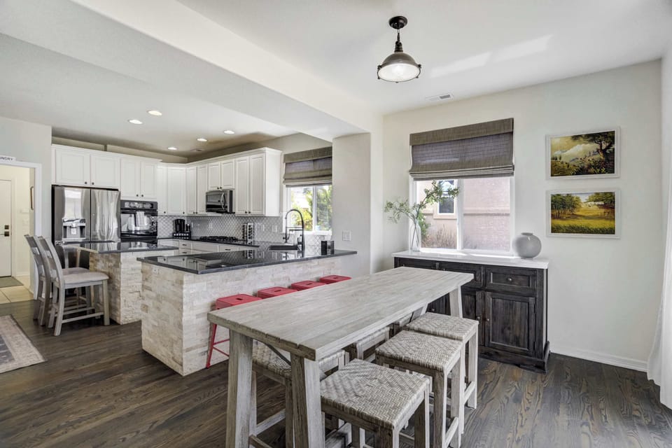 The heart of the home—this open-concept kitchen and dining space features a granite island with bar seating, rustic table for six, and sleek stainless steel appliances throughout.

