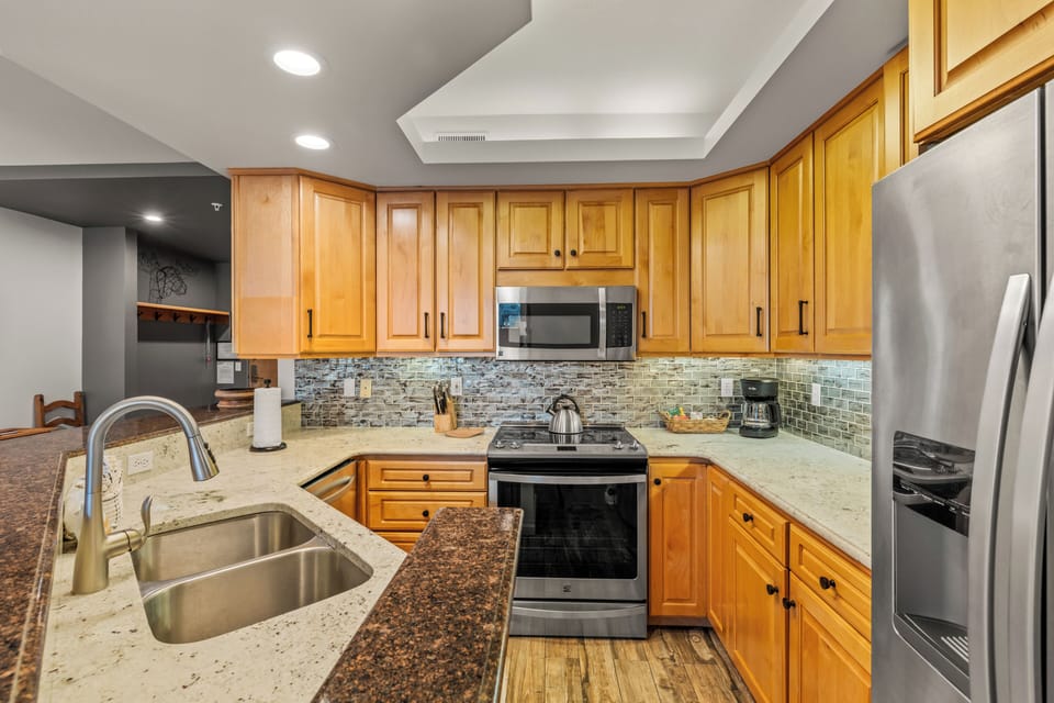 Your fully equipped kitchen awaits with stone counters, stainless appliances, and warm wood cabinets—perfect for creating memorable meals together.