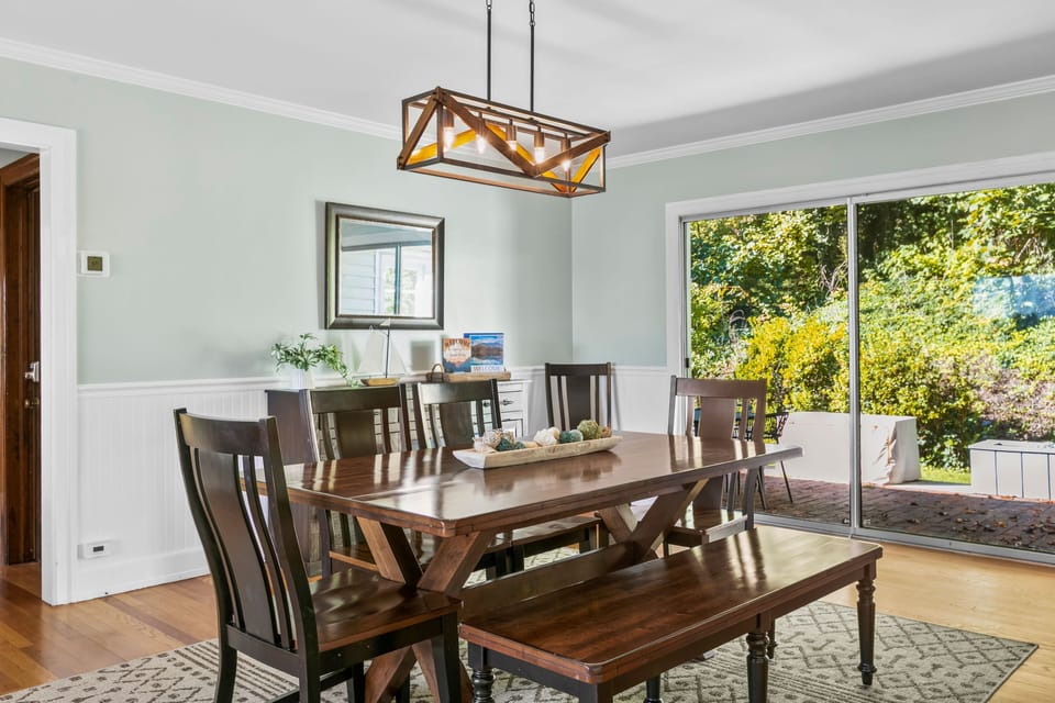 Dining area featuring a wooden trestle table, bench seating, and sliding doors to the patio.